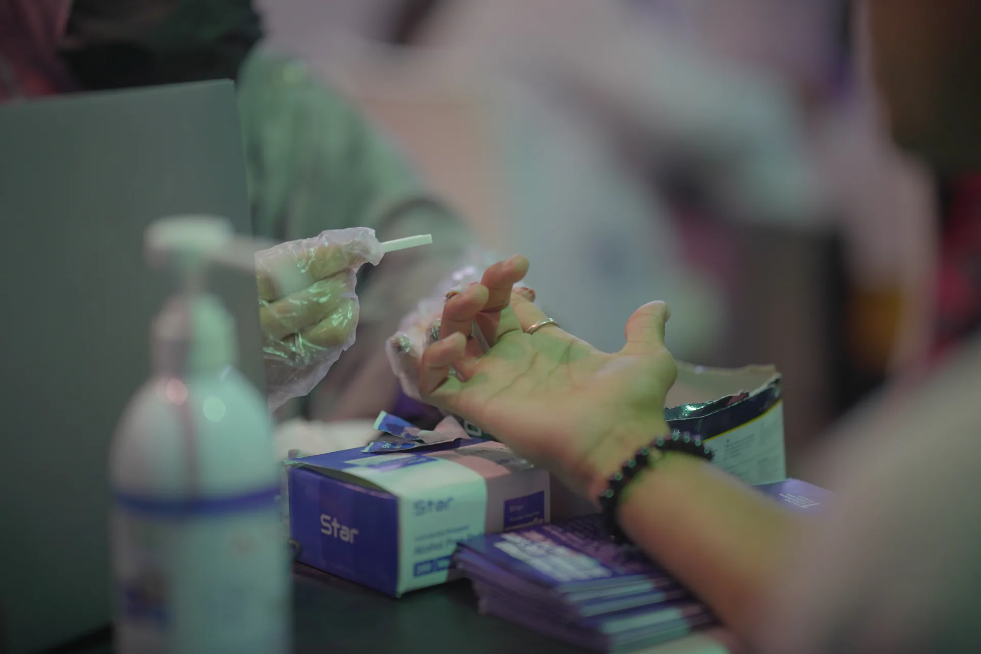 A lab technician taking a finger-prick blood sample