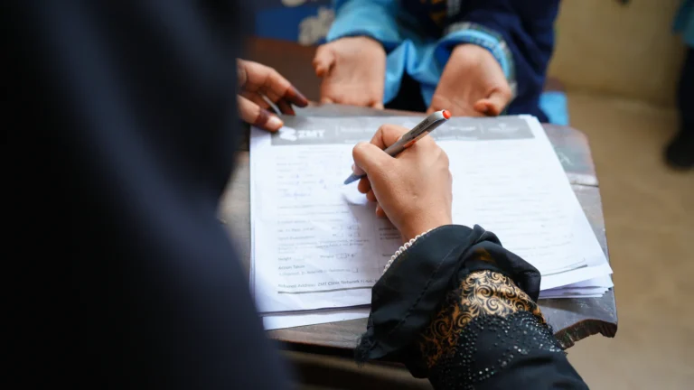 A ZMT staff member filling in a patient's registration form