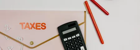 Calculator and pens on a folder labelled Taxes, for working out the tax credit on a corporate donation