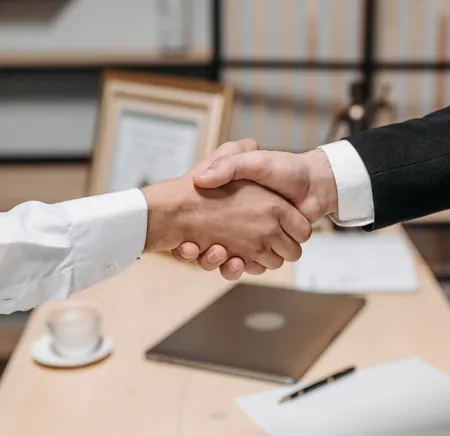 Two people shaking hands in an office, a CSR partnership in Pakistan being agreed