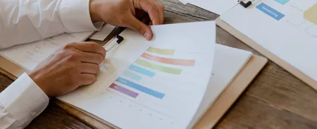 Hands reviewing a printed report with bar charts, as donors check how sadaqah is used