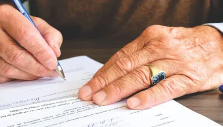 Older man signing a document, as when writing a wasiyyah that leaves a lasting gift