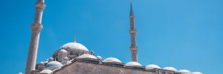 Mosque domes and minarets under a blue sky, a reminder of zakat and ongoing charity
